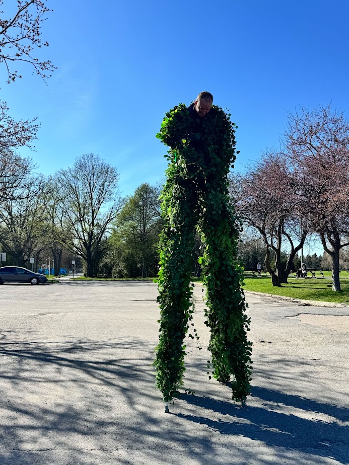 리에르 마르샹(Lierre Marchant)은 1.8미터 높이의 죽마에 네 발로 서서 나뭇잎으로 뒤덮인 거대한 존재로 돌아다니는 모습을 연출합니다. 도시의 녹지가 사라지고 몬트리올 곳곳에 나무가 쓰러지는 현실에 대한 대응으로 탄생한 그는 조용한 저항의 행위로서 도시 풍경을 돌아다닙니다. 나뭇잎으로 뒤덮인 그의 몸은 주변 환경과 자연스럽게, 때로는 너무나 잘 어우러집니다.